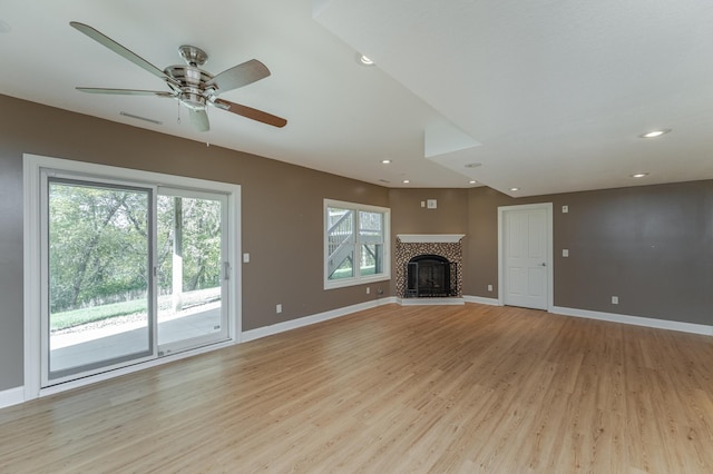 unfurnished living room with light hardwood / wood-style flooring, ceiling fan, a tile fireplace, and a wealth of natural light