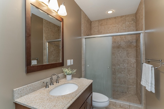 bathroom with toilet, a shower with shower door, vanity, and tile patterned floors