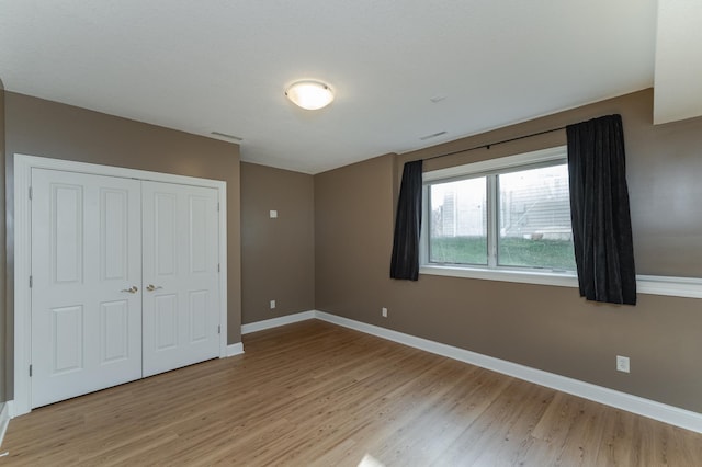 unfurnished bedroom with light hardwood / wood-style flooring and a closet