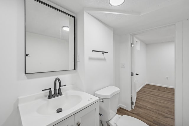 bathroom with vanity, wood-type flooring, a textured ceiling, and toilet