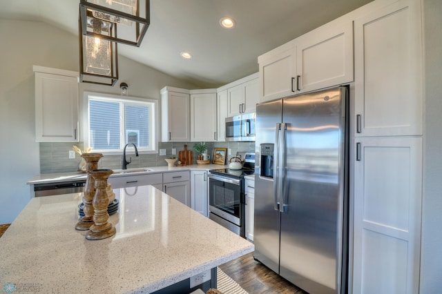 kitchen featuring lofted ceiling, stainless steel appliances, backsplash, a sink, and white cabinets