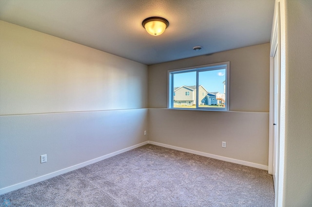 spare room featuring carpet floors and baseboards