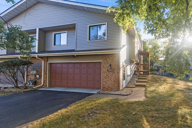 view of front of home with brick siding, a front lawn, an attached garage, and aphalt driveway