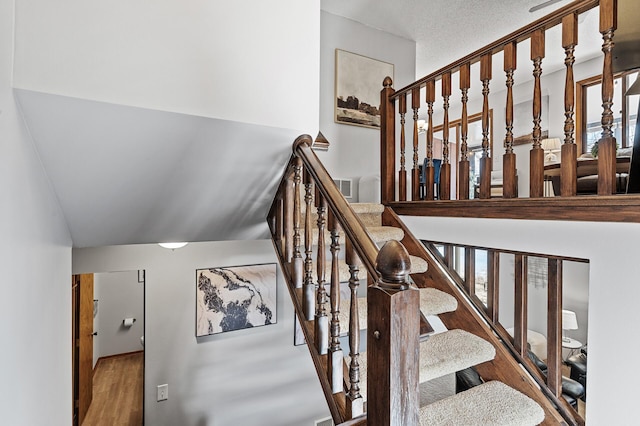 stairs with wood finished floors and visible vents