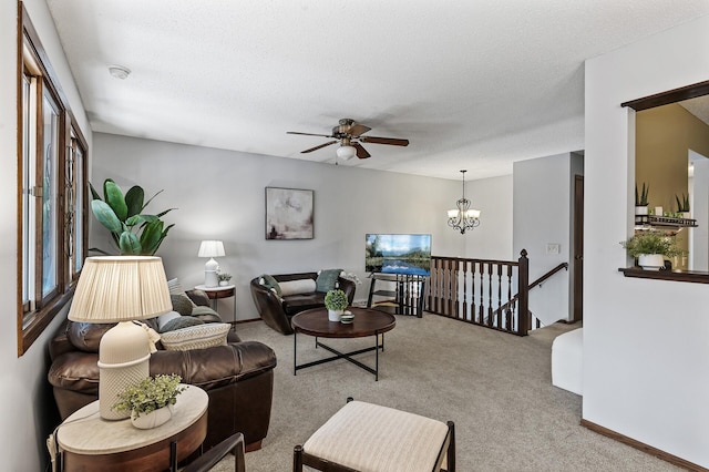 living room featuring a textured ceiling, carpet floors, ceiling fan with notable chandelier, and baseboards