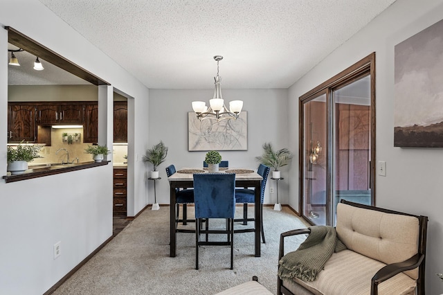 dining room with light carpet, an inviting chandelier, baseboards, and a textured ceiling