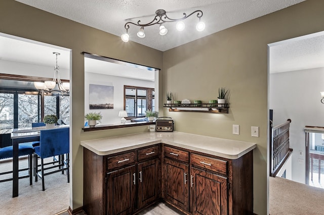 kitchen with light countertops, light carpet, a textured ceiling, and an inviting chandelier