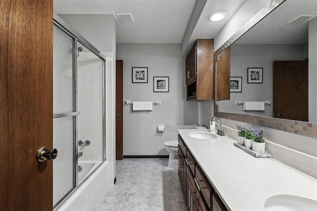 bathroom with double vanity, combined bath / shower with glass door, a sink, a textured ceiling, and baseboards