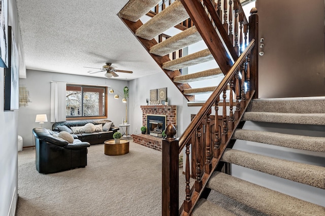 carpeted living room with a fireplace, stairway, a textured ceiling, and ceiling fan