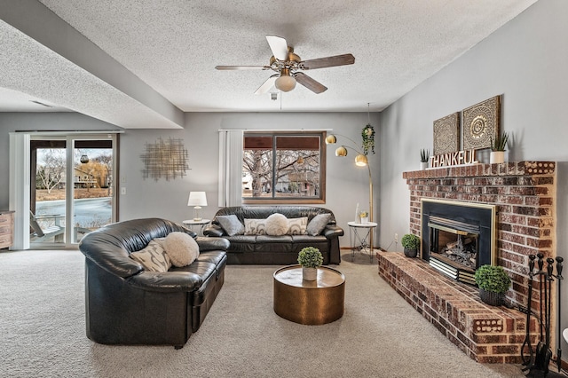 living room with a textured ceiling, carpet floors, a fireplace, and a ceiling fan