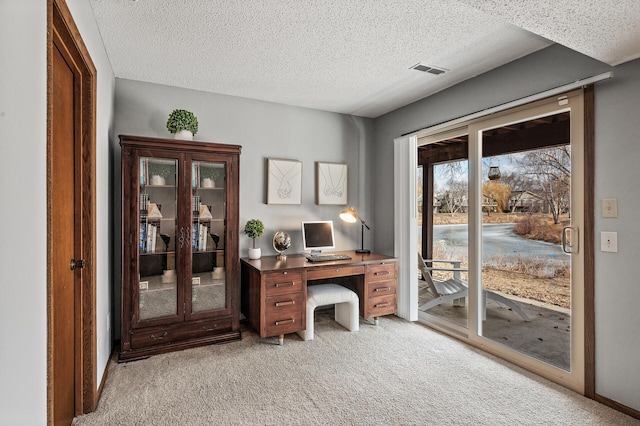 office area featuring light colored carpet, visible vents, and a textured ceiling