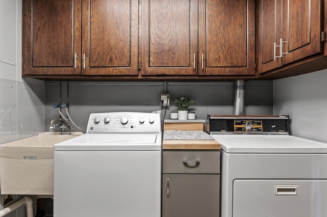 laundry room with cabinet space, separate washer and dryer, and a sink