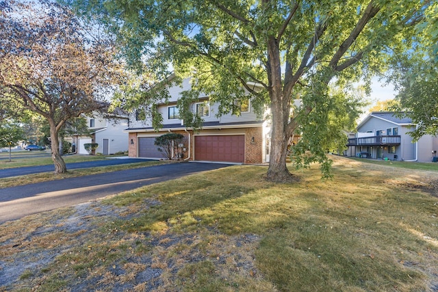 view of front of home with a garage, driveway, brick siding, and a front lawn