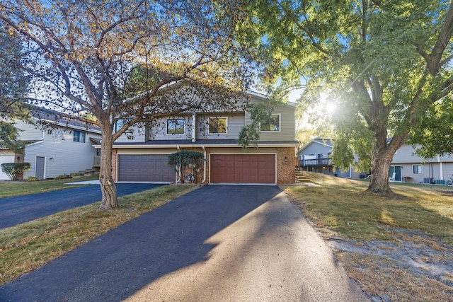 view of front of property with brick siding, a front lawn, an attached garage, and aphalt driveway