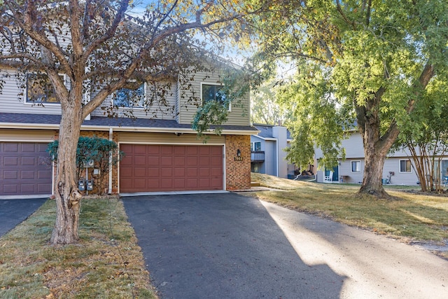 townhome / multi-family property featuring a front yard, brick siding, driveway, and an attached garage