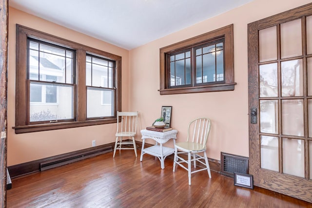 living area featuring a baseboard heating unit and hardwood / wood-style floors