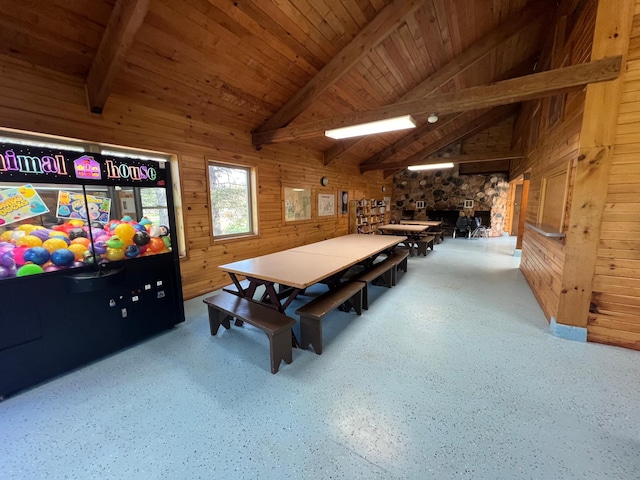 game room featuring wood ceiling, wooden walls, vaulted ceiling with beams, and a stone fireplace