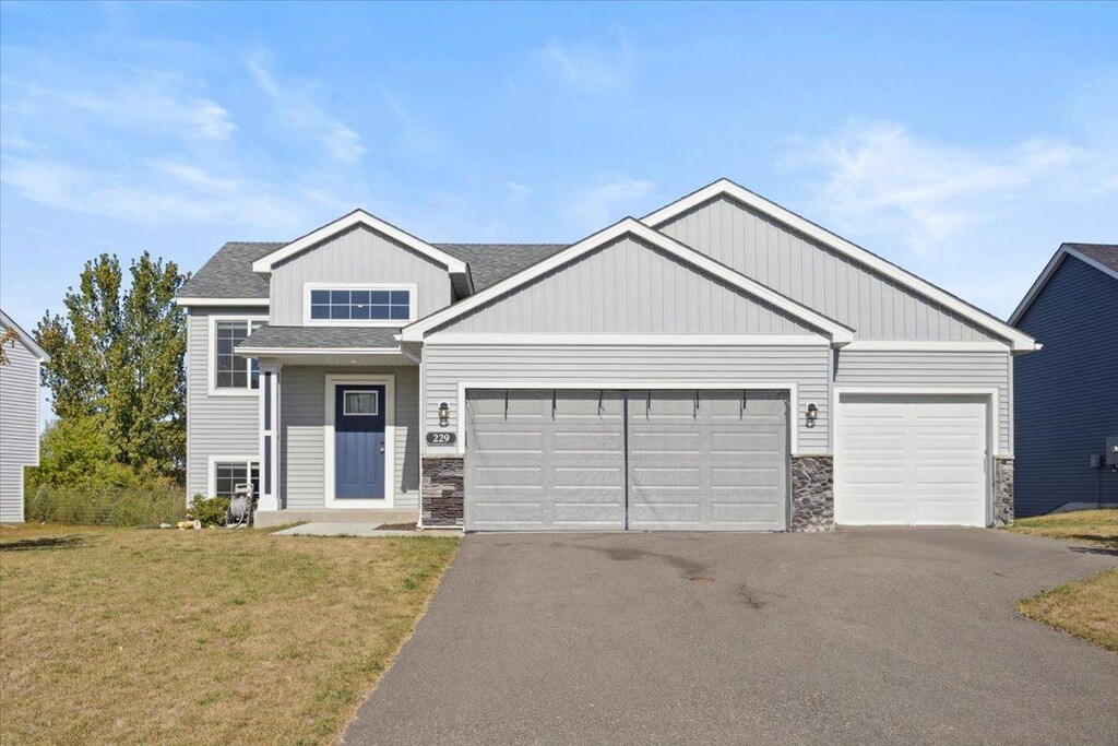 229 Terning Way, Howard Lake, MN 55349 - view of front facade featuring a front lawn, stone siding, a garage, and aphalt driveway