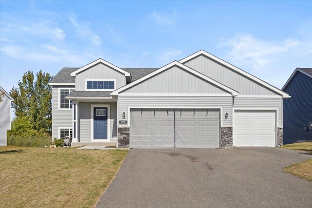 229 Terning Way, Howard Lake, MN 55349 - view of front facade featuring a front lawn, stone siding, a garage, and aphalt driveway