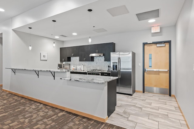 kitchen with kitchen peninsula, a breakfast bar area, stainless steel appliances, light hardwood / wood-style flooring, and decorative light fixtures