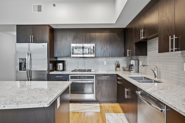 kitchen featuring light stone countertops, stainless steel appliances, light hardwood / wood-style floors, and sink