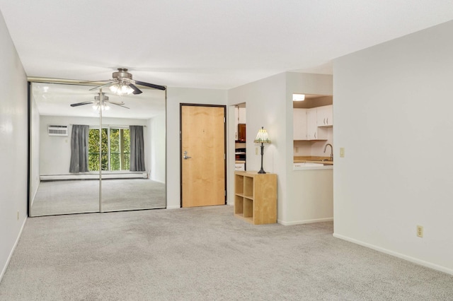 unfurnished living room with a baseboard radiator, sink, an AC wall unit, light carpet, and ceiling fan