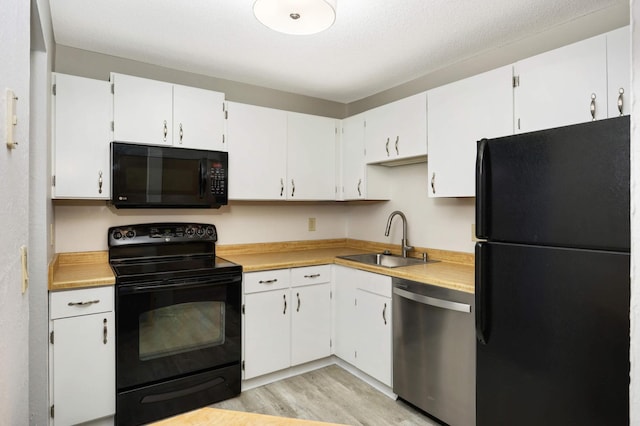 kitchen featuring black appliances, sink, a textured ceiling, white cabinets, and light hardwood / wood-style flooring