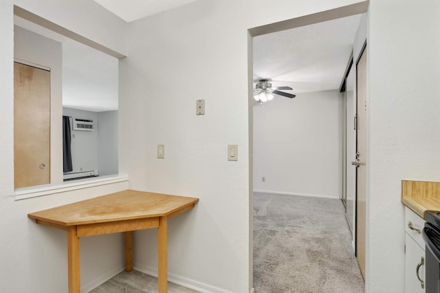 interior space featuring a wall mounted air conditioner, a textured ceiling, baseboard heating, and light colored carpet