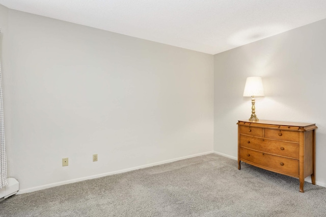 empty room featuring a baseboard radiator and light carpet