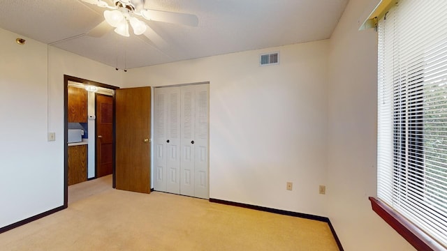 unfurnished bedroom with a textured ceiling, ceiling fan, light colored carpet, and a closet