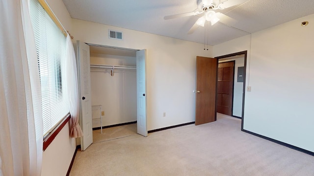 unfurnished bedroom featuring multiple windows, light carpet, ceiling fan, and a closet