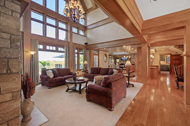 living room with an inviting chandelier, beam ceiling, and light hardwood / wood-style floors