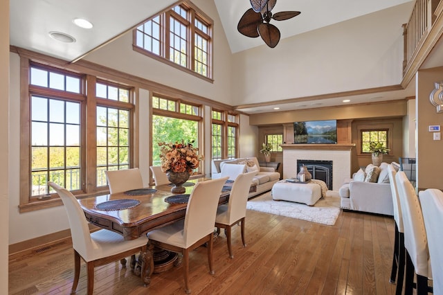 dining space featuring a brick fireplace, high vaulted ceiling, ceiling fan, and light hardwood / wood-style flooring