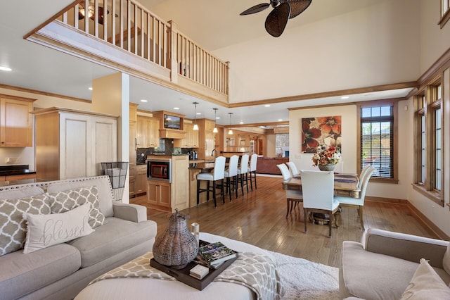 living room with a high ceiling, dark hardwood / wood-style flooring, and ceiling fan