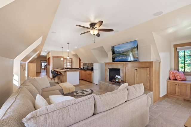 living room with a fireplace, lofted ceiling, light tile patterned floors, and ceiling fan