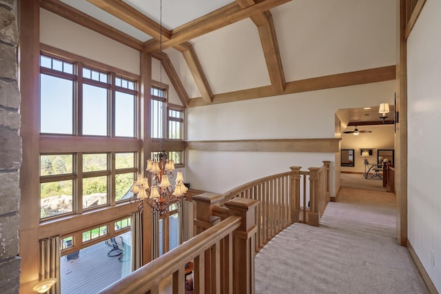 hall with high vaulted ceiling, an inviting chandelier, beamed ceiling, and light carpet