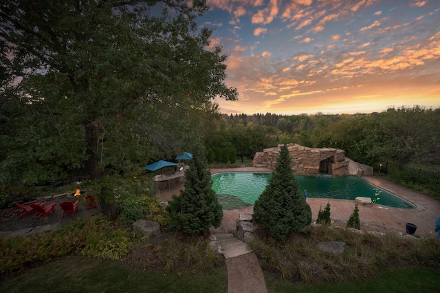 pool at dusk with a patio area