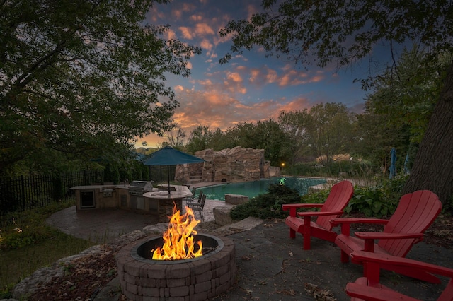 patio terrace at dusk with a fire pit and area for grilling