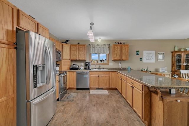 kitchen with pendant lighting, kitchen peninsula, stainless steel appliances, a breakfast bar, and light hardwood / wood-style floors