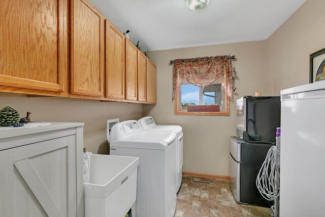 clothes washing area with cabinets, a textured ceiling, sink, and washing machine and clothes dryer