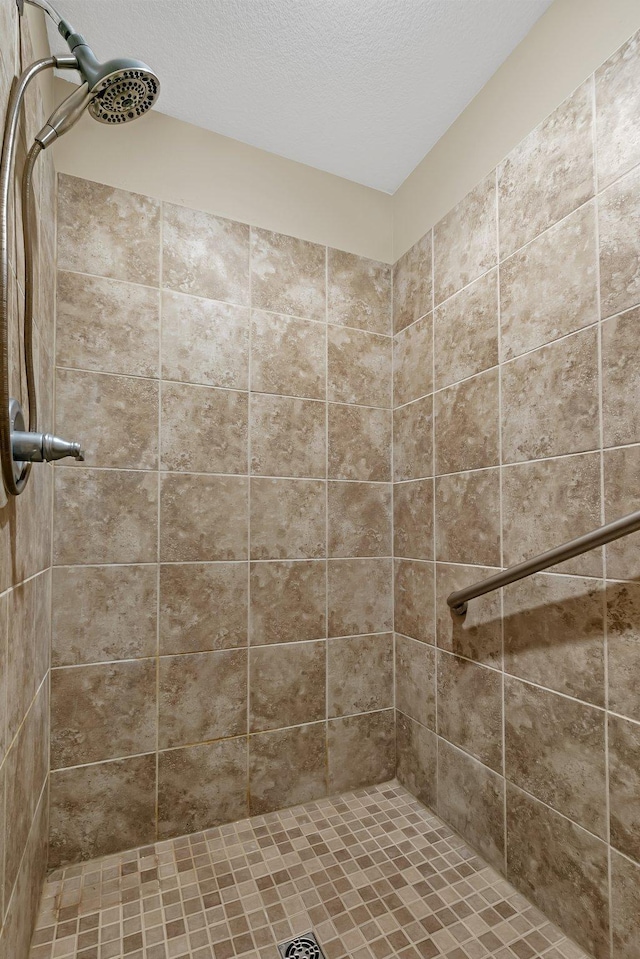 bathroom with a tile shower and a textured ceiling