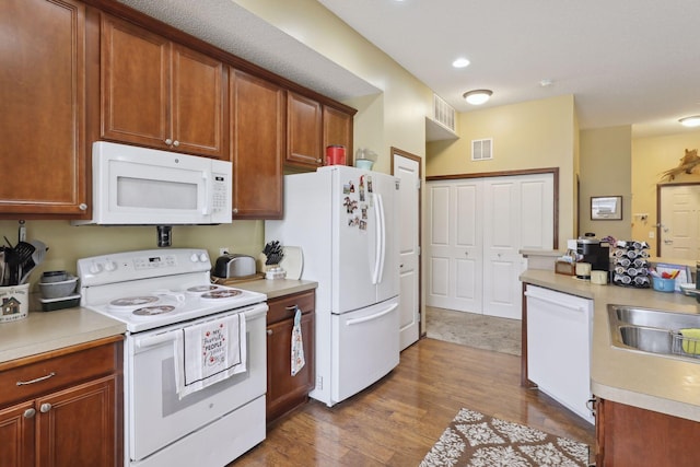 kitchen featuring white appliances, dark wood-type flooring, and sink