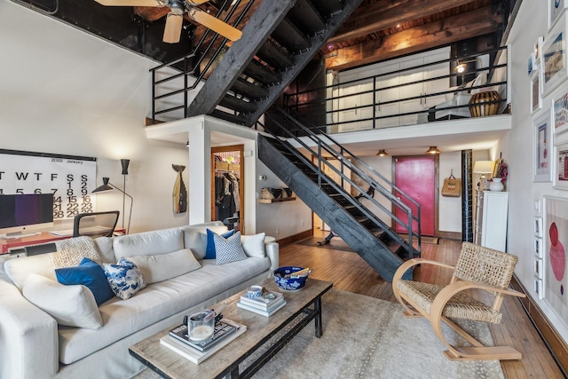 living room with ceiling fan, wood-type flooring, and a high ceiling