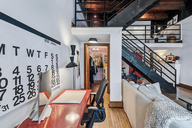 office with hardwood / wood-style floors and a towering ceiling