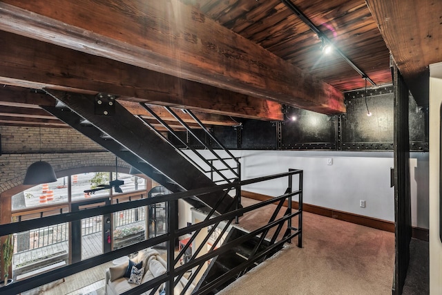 interior space featuring carpet, wooden ceiling, and brick wall