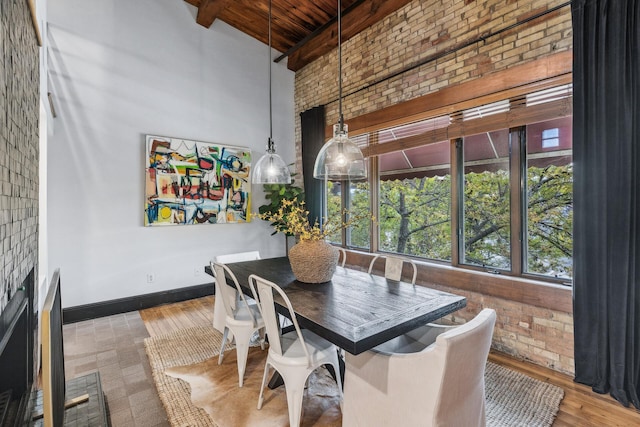 dining area with a high ceiling, brick wall, beamed ceiling, wood-type flooring, and wood ceiling