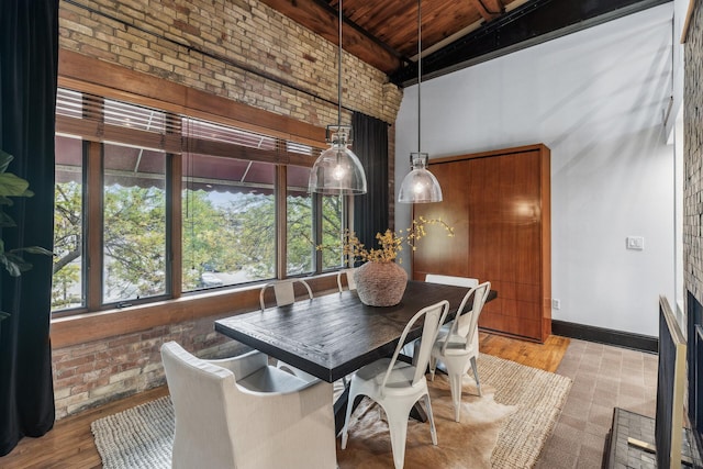 dining room featuring beam ceiling, light hardwood / wood-style flooring, wooden ceiling, and brick wall