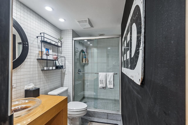 bathroom with vanity, a shower with shower door, tile walls, and toilet