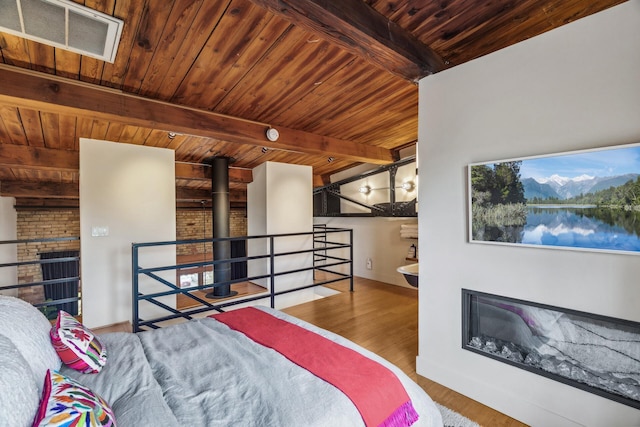 unfurnished bedroom with beam ceiling, a stone fireplace, wood ceiling, and wood-type flooring