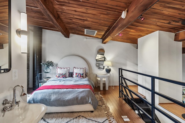 bedroom with beamed ceiling, hardwood / wood-style flooring, and wood ceiling